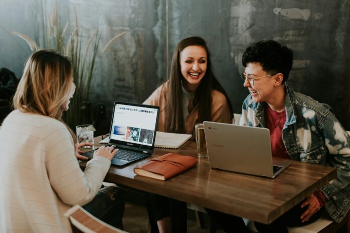 jovens sentados com computador na mesa e rindo